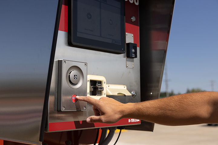 a hand presses a button on a red BTEK Scales indicator