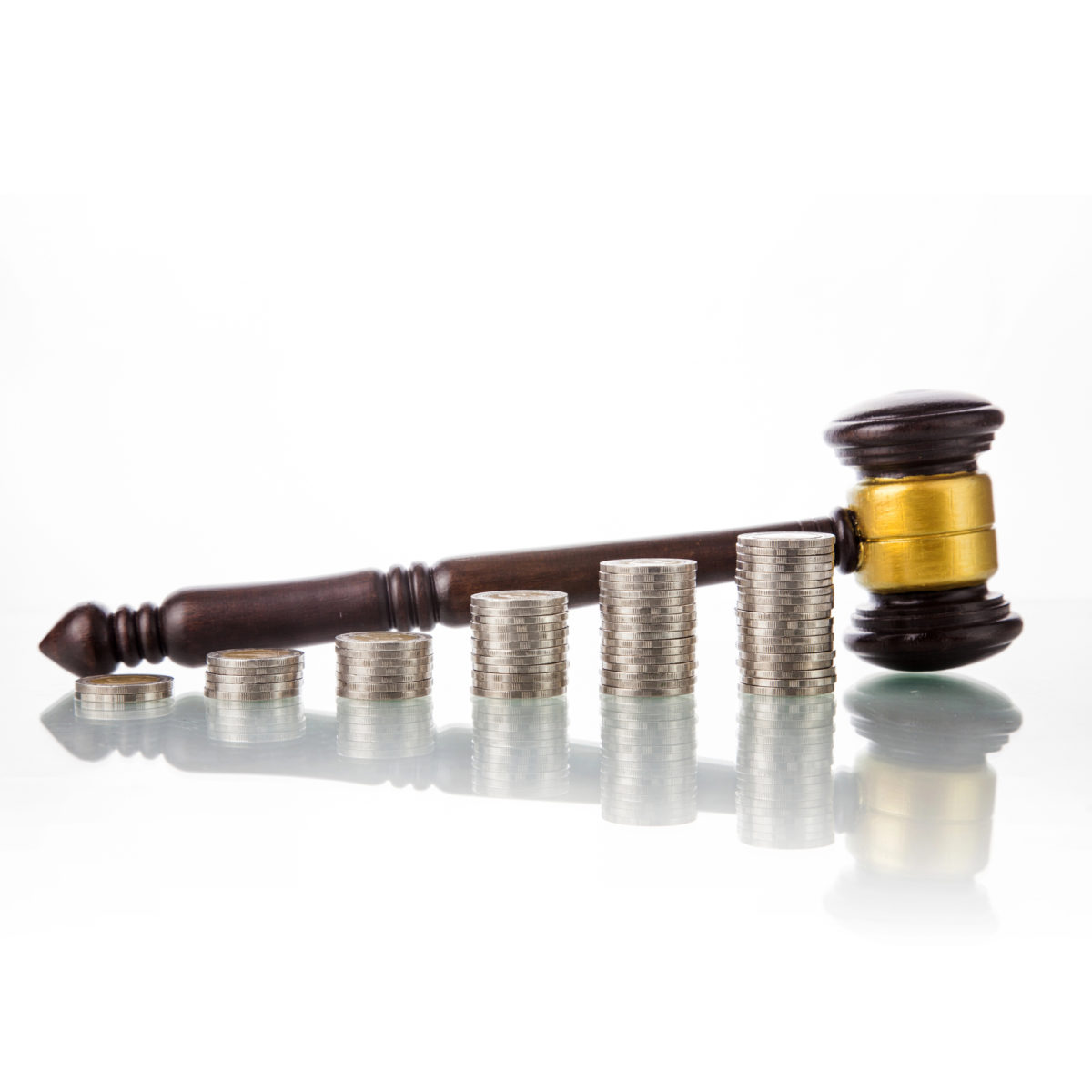 Stacks of silver coins with a judge's gavel on a white background representing the legal cost of inaccuracy